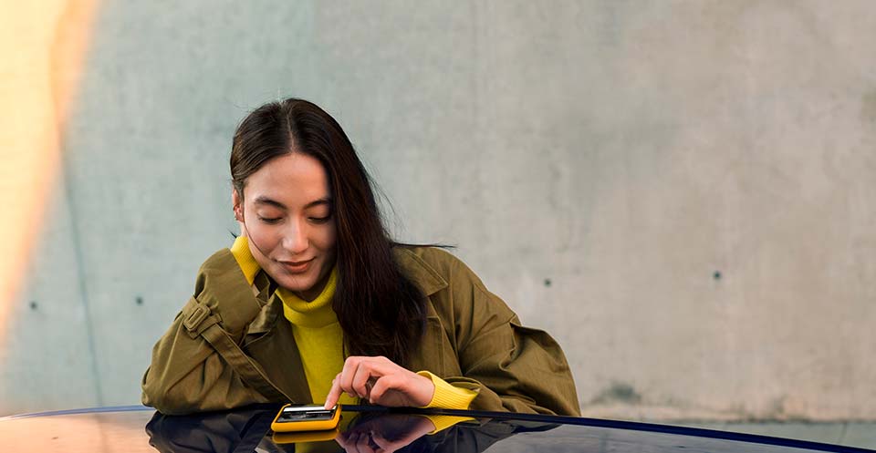 A woman using Volkswagen Car-Net to connect to her car from her mobile phone